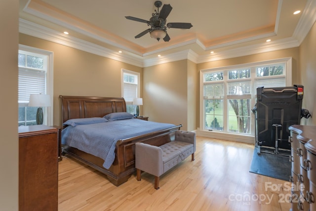 bedroom with a raised ceiling, light hardwood / wood-style floors, crown molding, and ceiling fan