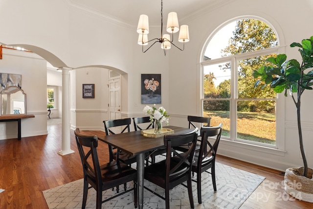 dining area featuring a notable chandelier, ornate columns, hardwood / wood-style flooring, and ornamental molding