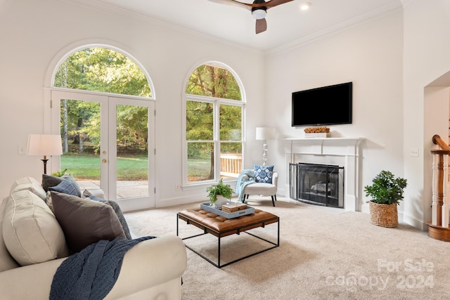 carpeted living room featuring crown molding, a high ceiling, and ceiling fan