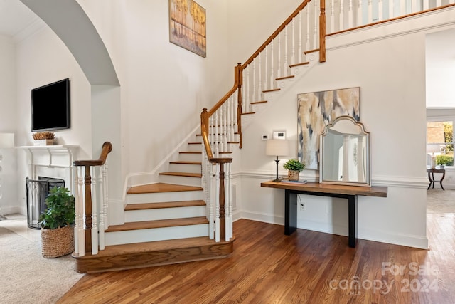 stairway with crown molding, hardwood / wood-style floors, and a high ceiling