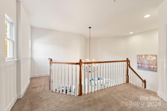 hall featuring carpet floors and a chandelier