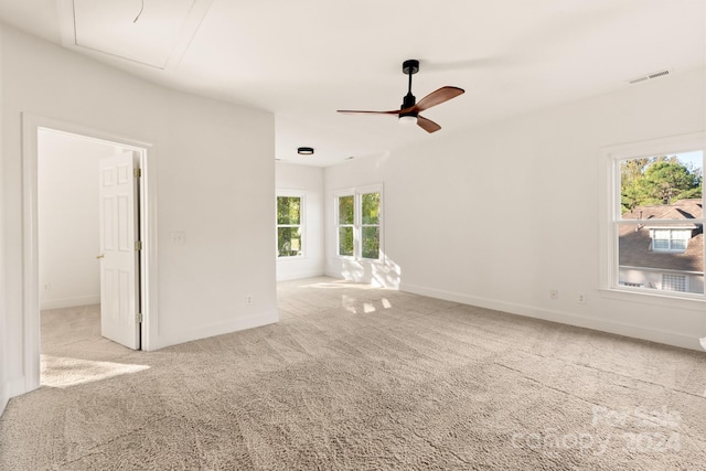 unfurnished living room featuring ceiling fan, a wealth of natural light, and light colored carpet