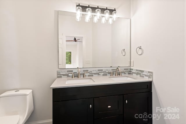 bathroom featuring vanity, toilet, and tasteful backsplash