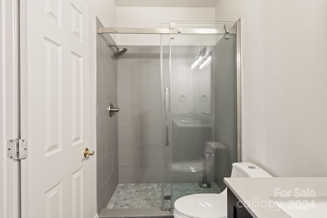 bathroom featuring vanity, toilet, and a shower with door