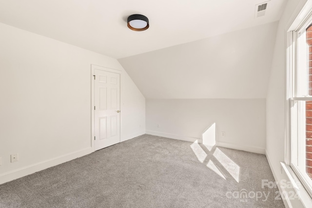 bonus room with vaulted ceiling and light carpet