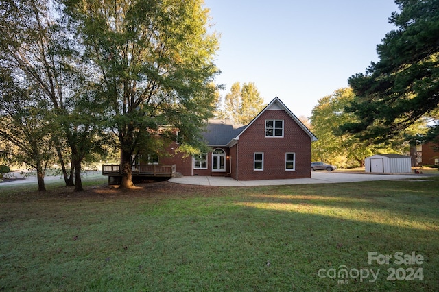 back of property with a patio, a storage shed, a deck, and a lawn