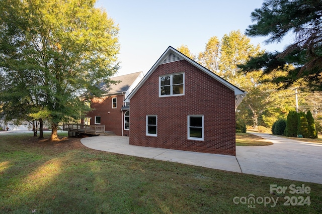 view of side of home featuring a yard and a wooden deck