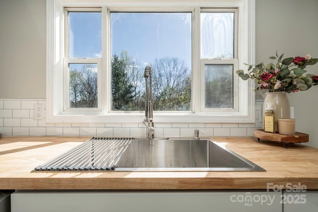 room details with tasteful backsplash, butcher block counters, and sink