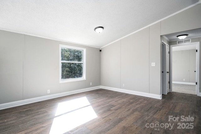 empty room with a textured ceiling, dark hardwood / wood-style floors, and crown molding