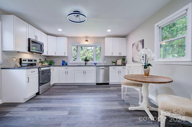 kitchen featuring appliances with stainless steel finishes, dark hardwood / wood-style flooring, sink, and white cabinets