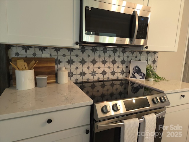 kitchen featuring decorative backsplash, stainless steel appliances, and white cabinets