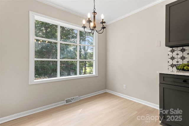 unfurnished dining area featuring ornamental molding, plenty of natural light, an inviting chandelier, and light hardwood / wood-style floors