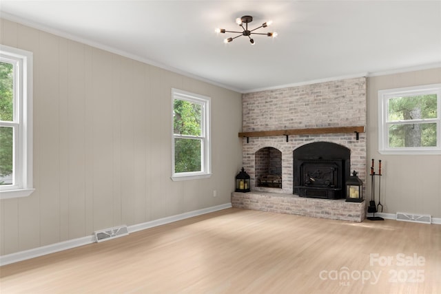 unfurnished living room featuring a fireplace, crown molding, a wealth of natural light, and hardwood / wood-style flooring