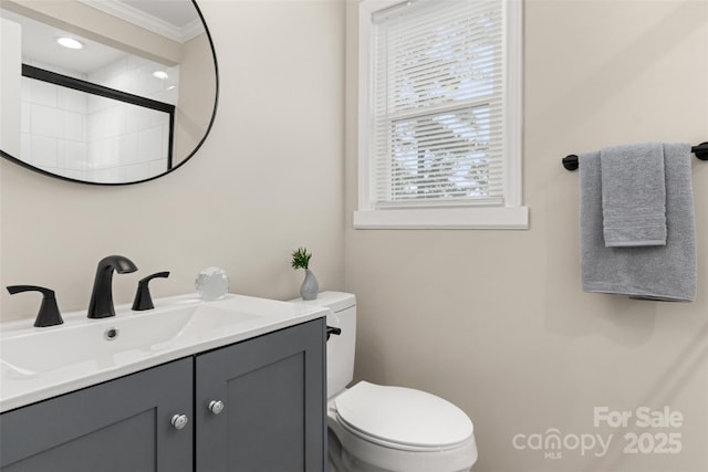 bathroom featuring vanity, crown molding, toilet, and a healthy amount of sunlight