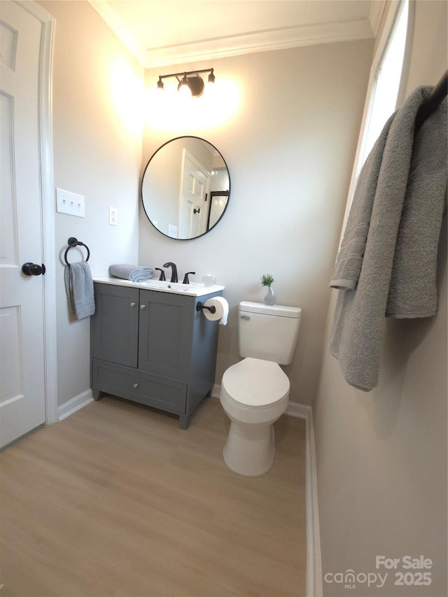 bathroom featuring hardwood / wood-style flooring, crown molding, vanity, and toilet