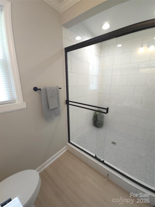 bathroom featuring ornamental molding, hardwood / wood-style floors, an enclosed shower, and toilet