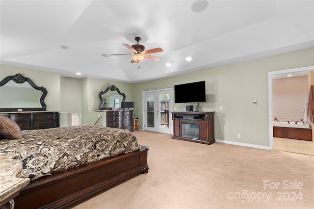 bedroom with ceiling fan, light colored carpet, and ensuite bath