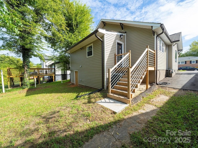 back of property with a deck and a lawn