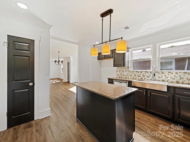 kitchen featuring light stone countertops, sink, a center island, and hanging light fixtures