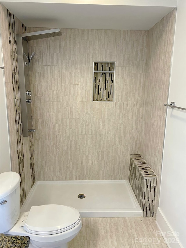 bathroom with a tile shower and toilet