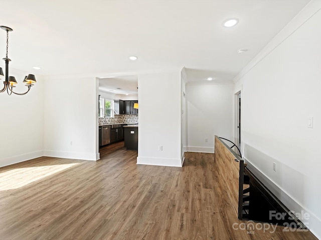 unfurnished living room with a chandelier, wood-type flooring, and crown molding