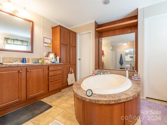 bathroom featuring a wealth of natural light, tile patterned floors, a textured ceiling, and vanity