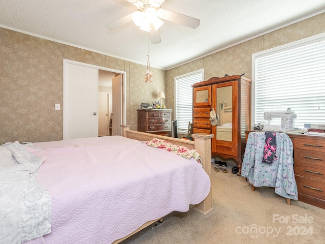 carpeted bedroom featuring ceiling fan, a textured ceiling, and ornamental molding