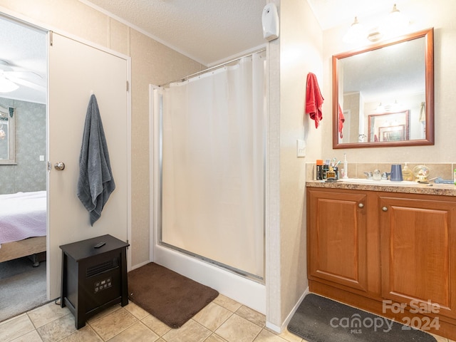 bathroom featuring ceiling fan, vanity, curtained shower, a textured ceiling, and tile patterned flooring