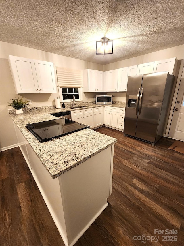 kitchen featuring light stone counters, appliances with stainless steel finishes, kitchen peninsula, and white cabinets