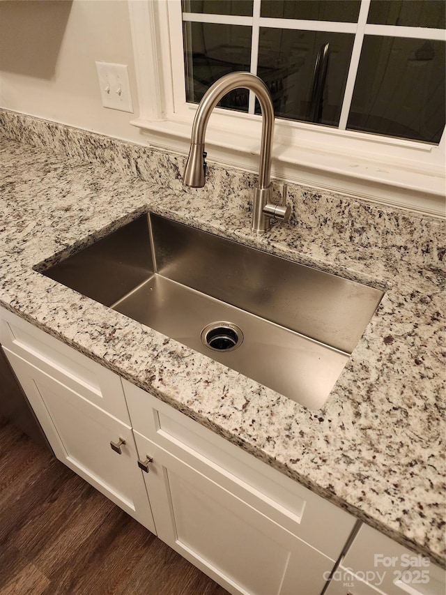 interior details with light stone countertops, sink, dark wood-type flooring, and white cabinets