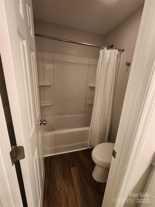 bathroom featuring hardwood / wood-style floors, shower / tub combo with curtain, a textured ceiling, and toilet