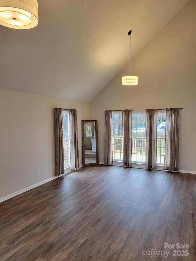 spare room with a healthy amount of sunlight, dark hardwood / wood-style floors, and high vaulted ceiling