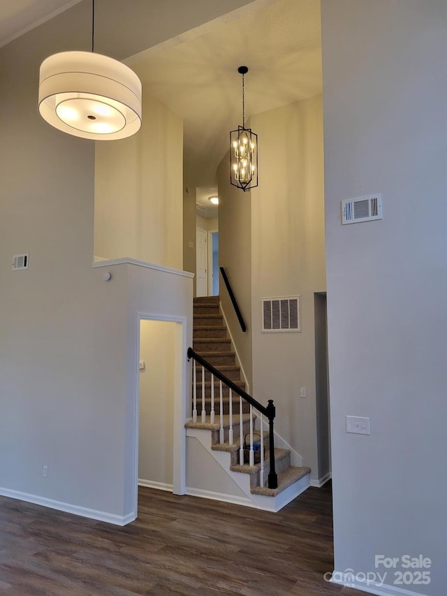 stairway with hardwood / wood-style floors and a high ceiling