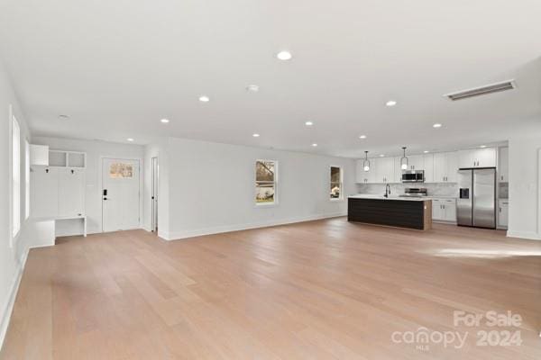 unfurnished living room featuring light hardwood / wood-style flooring and sink