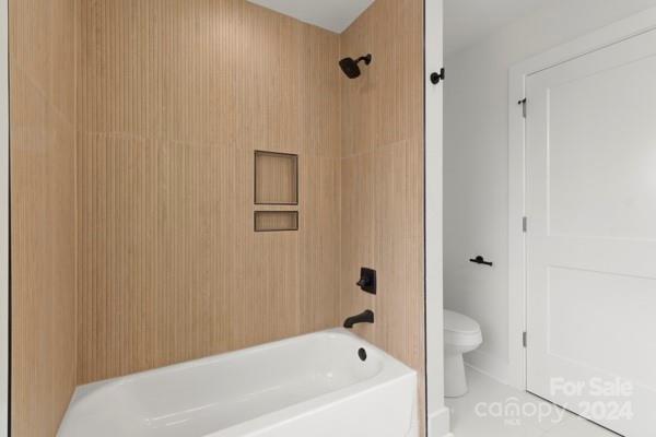 bathroom with tiled shower / bath combo and toilet