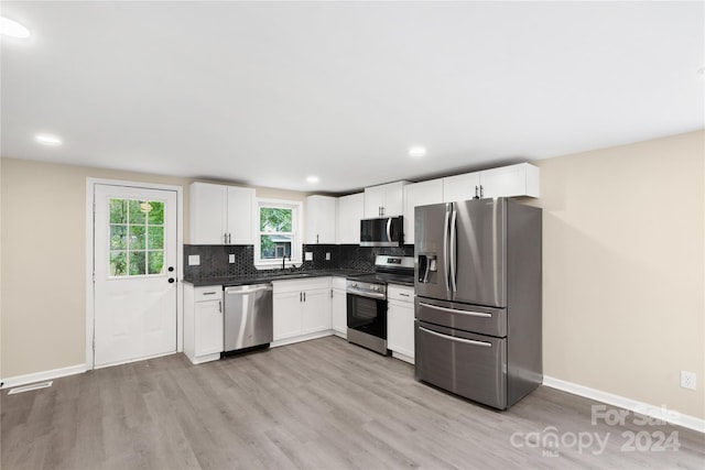 kitchen featuring white cabinetry, light hardwood / wood-style flooring, backsplash, sink, and appliances with stainless steel finishes