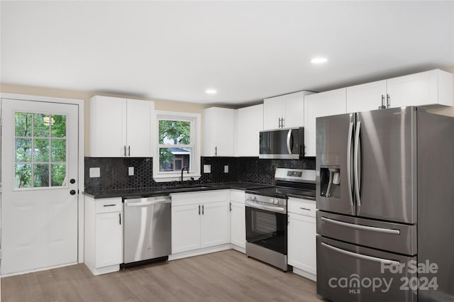 kitchen featuring white cabinets, stainless steel appliances, sink, and light hardwood / wood-style floors