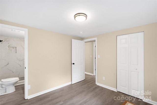 unfurnished bedroom featuring ensuite bath, hardwood / wood-style flooring, and a closet