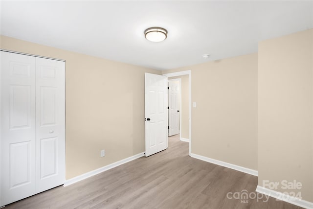 unfurnished bedroom with light hardwood / wood-style flooring and a closet