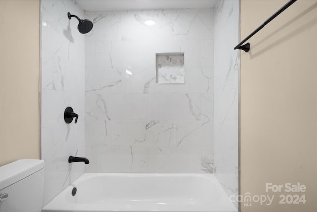 bathroom with tiled shower / bath combo and toilet