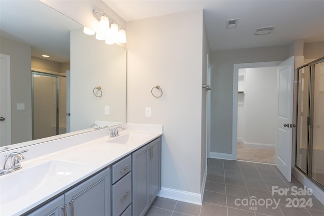 bathroom with tile patterned floors, a shower with door, and vanity