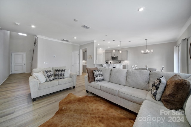 living room with crown molding, a chandelier, and light hardwood / wood-style floors