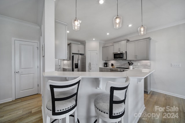 kitchen featuring light wood-type flooring, a kitchen breakfast bar, stainless steel appliances, and pendant lighting