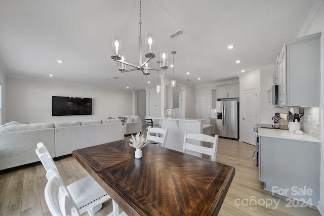 dining space with an inviting chandelier, crown molding, and light hardwood / wood-style flooring