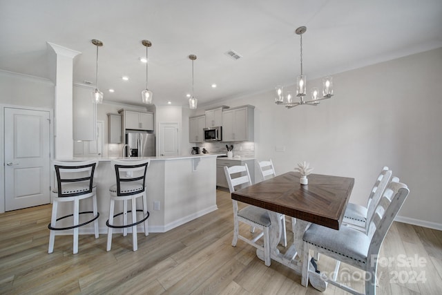 kitchen with light wood-type flooring, ornamental molding, decorative light fixtures, appliances with stainless steel finishes, and gray cabinetry