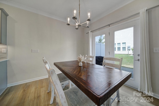 dining space with light wood-type flooring, crown molding, and a chandelier