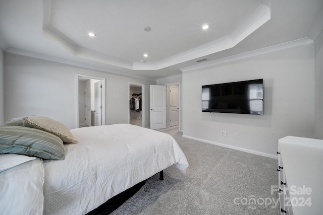 bedroom with crown molding, a walk in closet, and a tray ceiling