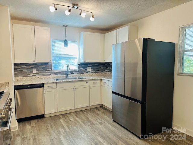 kitchen with a wealth of natural light, light wood-type flooring, sink, and appliances with stainless steel finishes