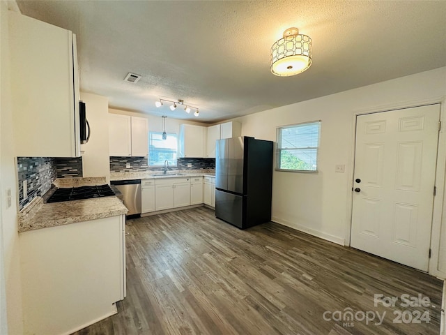 kitchen with a textured ceiling, dark hardwood / wood-style floors, backsplash, stainless steel appliances, and sink