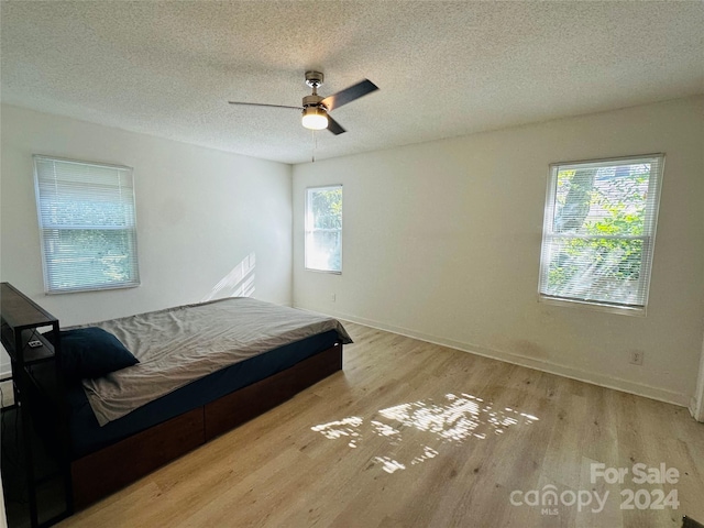 bedroom featuring a textured ceiling, light hardwood / wood-style flooring, and ceiling fan